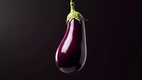 pngtree-glossy-purple-eggplant-with-green-stem-against-dark-background-fresh-vibrant-image_17612865
